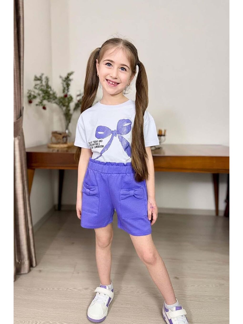 Kız Çocuk Üzerinde Digital Kurdela Basklı T-Shirt ve Fiyonk Cep Detaylı Lila Şortlu Takım