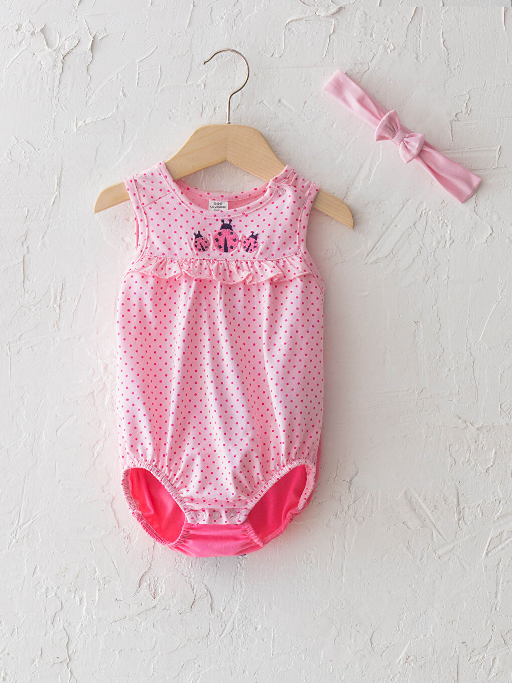 Дөңгелек жағалы горошекпен қыз балаға арналған түймесі бар боди және шашқа арналған таспа