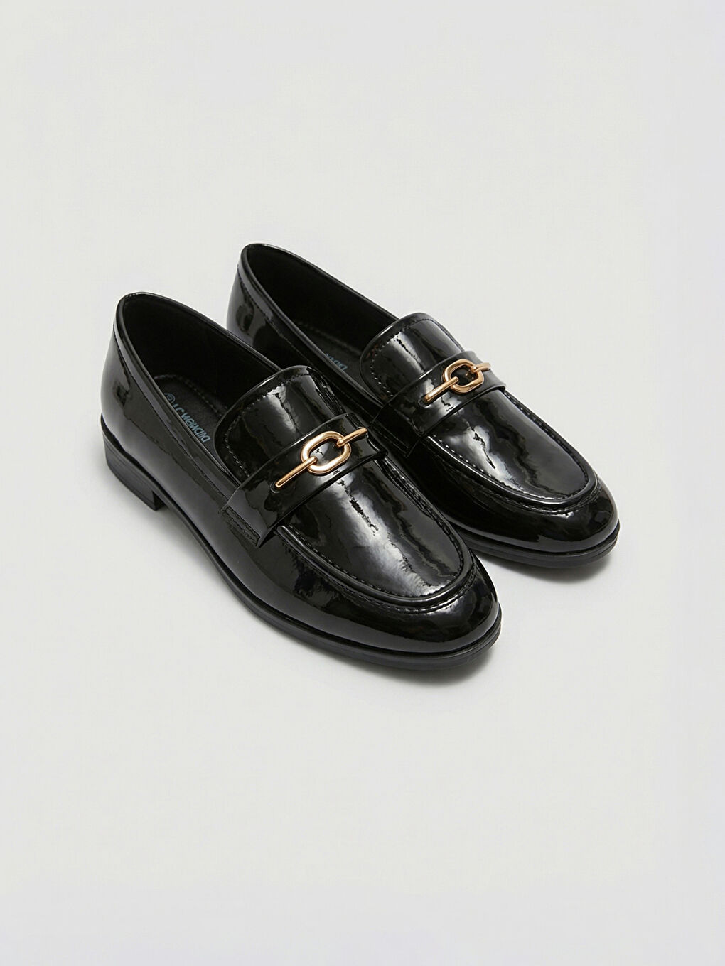 Lakovane cipele na štiklu, uzdignute metalnim detaljima.